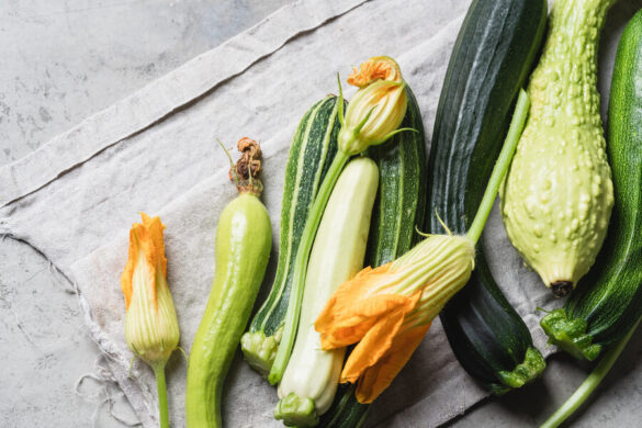 Des fleurs femelles et des courgettes étalées sur une table en bois.