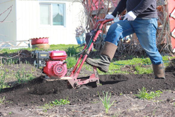Un fermier creusant le sol dans le jardin avec un motoculteur pour cultiver