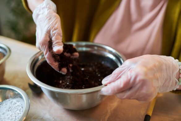 Une personne qui porte un gant et prépare son terreau dans un pot